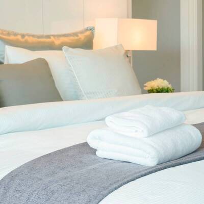 Bettwäsche und flauschige Handtücher auf einem breiten Bett