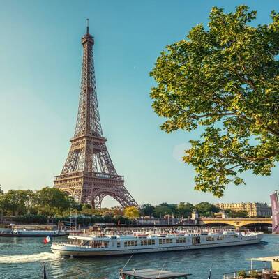 Blick auf den Eiffelturm. Ein Boot fährt davor auf der Seine.