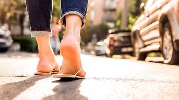 Füße in Flip Flops, die über eine Straße laufen